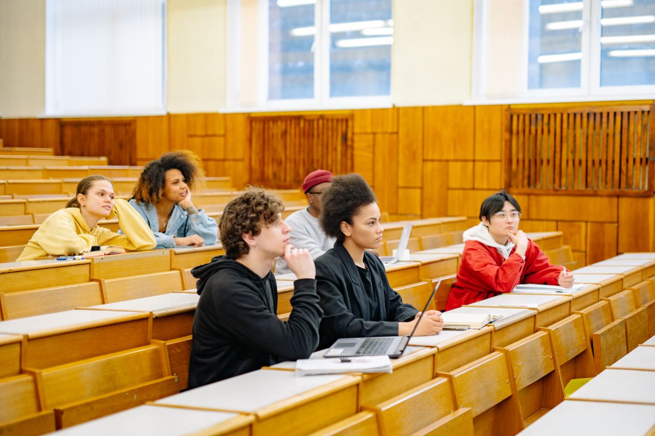 Students of various backgrounds attentively listening in a university lecture hall.